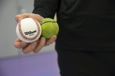Sotkamon Jymyn Konsta Kurikka esittelee baseball palloa ja pesäpalloa vierekkäin.