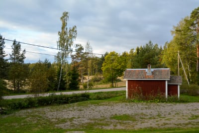 Landsväg går genom ett åkerlandskap. På ena sidan av vägen finns ett litet rött skjul.