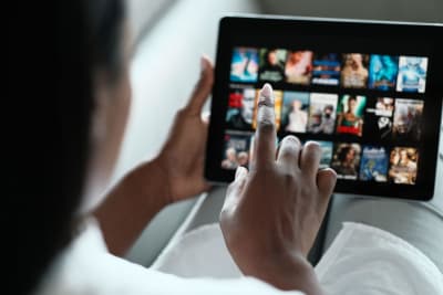 En kvinna skrollar i Netflix utbud på en pekplatta.