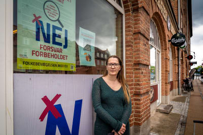 Karina Rohr står mot en vägg med en skylt med texten Nej forsvar forbeholdet.