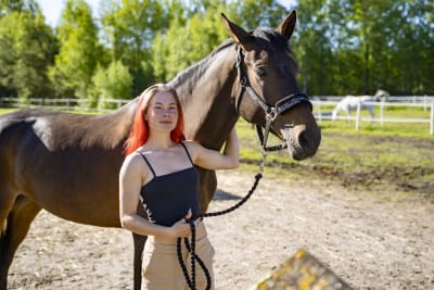 Kvinna med rött hår tillsammans med en häst.