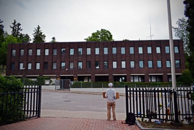 En ensam kvinna står med två skyltar framför det stora ryska konsulatet.