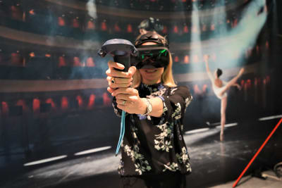 En kvinna med 3D-glasögon som riktar en joystick mot åskådaren.