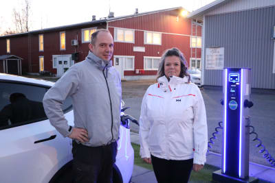 En man och en kvinna står vid en laddningsstation för elbilar.