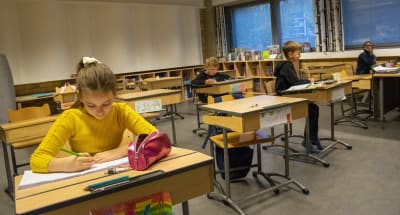 Skolelever i Salo svenska skola sitter vid pulpeten och skriver. 