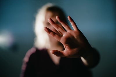En person döljer sitt ansikte genom att höja en hand. 