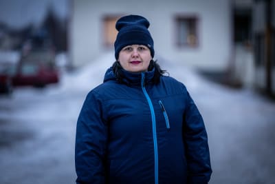 Kvinna i blå jacka och blå mössa i vintrig miljö