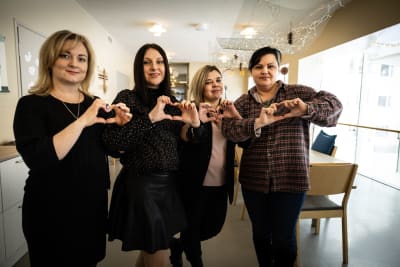 En grupp av kvinnor håller upp händerna formade till hjärtan