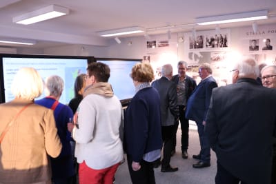 Ett flertal människor står i ett museum och diskuterar med varandra.