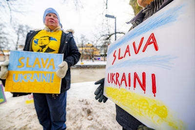 Kvinna håller i en skylt där det står Slava Ukraini