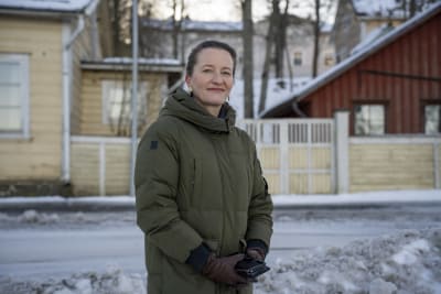 En kvinna i vinterkläder, Johanna Backas, står framför en tomt där det får byggas ett hotell i terrasser.