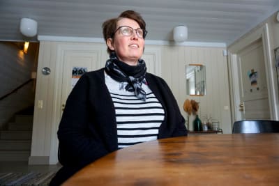 Kvinna i randig tröja sitter vid ett bord.