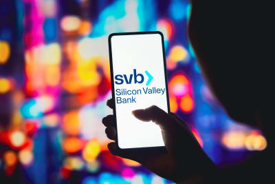 En person håller upp en telefon där det på skärmen står "Silicon Valley Bank".
