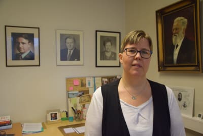 Kvinna i glasögon sitter i sitt arbetsrum.