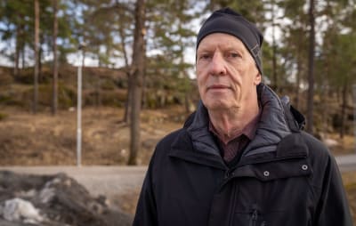 Jack Stenberg ser in i kameran. Han har mössa på huvudet och i bakgrunden syns några tallar.