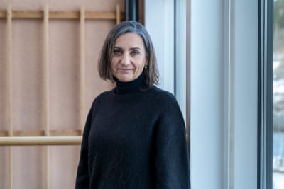 Teresa Silva står vid ett fönster och tittar in i kameran.T