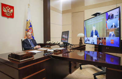 Vladimir Putin istuu työhuoneessaan ja osallistuu videokonferessiin.