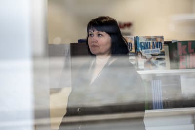 Porträttfoto genom fönster av kvinna i mörk skjorta
