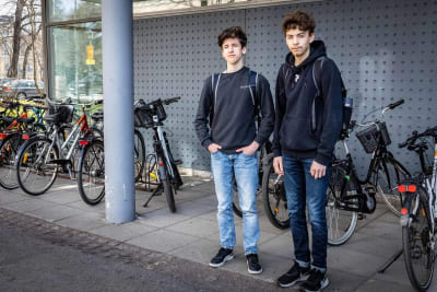 Porträttfoto av två pojkar som står framför en rad med cyklar