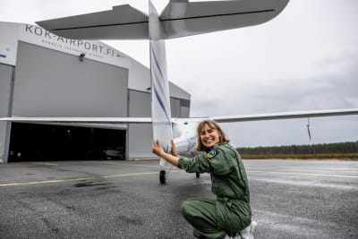 Kvinna i grön flygoverall inspekterar ultralätt flygplan