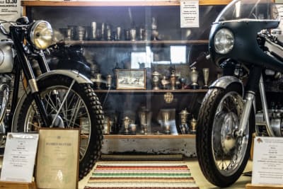 Två veteranmotorcyklar "nos mot nos", i bakgrunden ett vitrinskåp med prispokaler