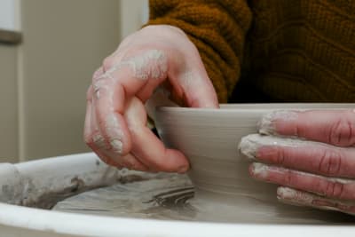 Händer som drejar en skål av lera. 
