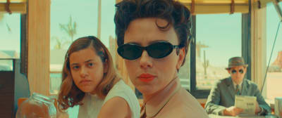 Scarlett Johansson i svarta glasögon sitter bredvid Grace Edwards som spelar hennes dotter i filmen Asteroid City. 