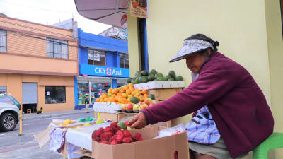 Kvinna säljer frukt vid ett stånd på gatan i san Vicente i Ecuador.