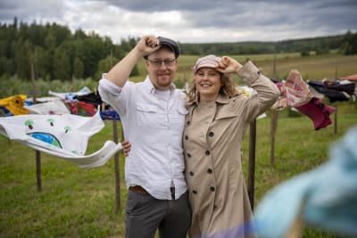 Två personer står bredvid varandra och håller i sina hattar.