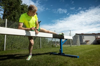 Man i träningskläder stretchar på bom