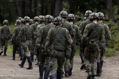 Varusmiehiä marssimassa metsässä.