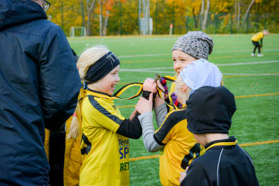 Fotbollsflickor glädjs över sina medaljer och visar upp dem för varandra.