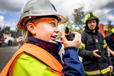 Ung tjej i brandkårsmundering pratar i walkie talkie under brandkårsövning.