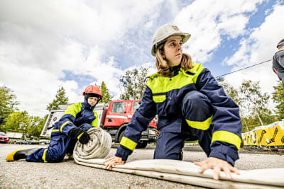 Brandkårsunga rullar ut slangar under brandkårsövning.