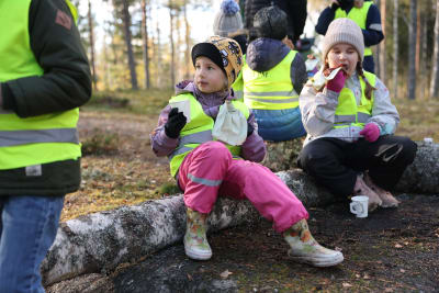 Barn äter grillkorv i skogen.