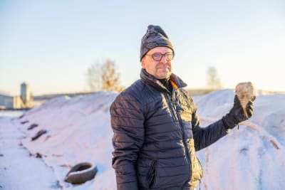 En man som tittar in i kameran medan han håller i en sockerbeta.