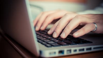 Närbild av händer som använder en bärbar dators tangentbord.