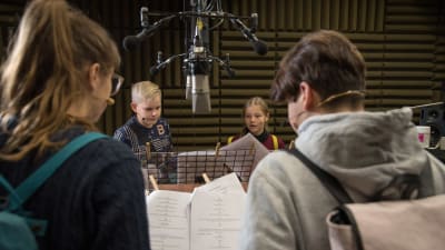 Fyra ungdomar står i en studio och spelar in repliker till ett audiodrama.