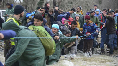 Flyktingar tar sig över en flod för att hitta alternativa rutter för att ta sig till den grekisk-makedoniska gränsen nära Idomeni.