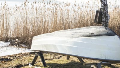 En liten båt på torra land, upp och ner på bockar.