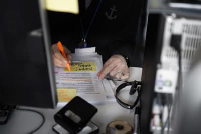 Arbetstagare jobbar på kontor, stryker under i text, i förgrunden dator.