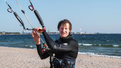 Leijalautailija Mikael Hyryläinen seisoo Tulliniemen rannalla Hangossa ja pitää kiinni leijastaan.