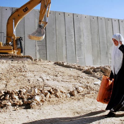 Palestiinalainen nainen kävelee israelilaisten rakentaman muurin vierustalla Itä-Jerusalemissa.
