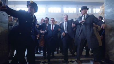 Frank Sheeran (Robert de Niro) eskorterar Jimmy Hoffa (Al Pacino) till domstolen, de är omringande av poliser och män.