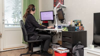 Person sitter framför dator i hemmet.