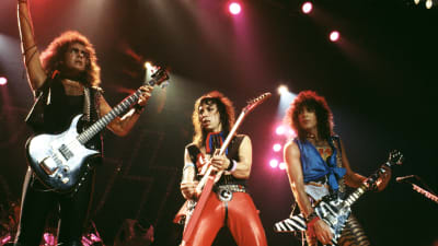 Tre män spelar gitarr på rockkonsert.