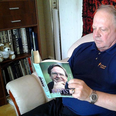 Pauli Salminen lukee kirjaa nojatuolissa. 