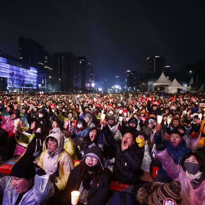 Kuvassa mielenosoittajia Soulin pääkadulla. Mielenosoittajilla kylttejä ja he vaativat presidenttiä eroamaan.