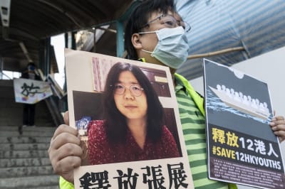 En man håller upp ett plakat med bild på en svarthårig kvinna och kinesiska tecken.