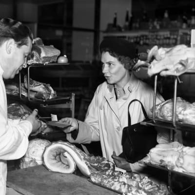 Kvinna köper kött med en ransoneringskupong i butik.